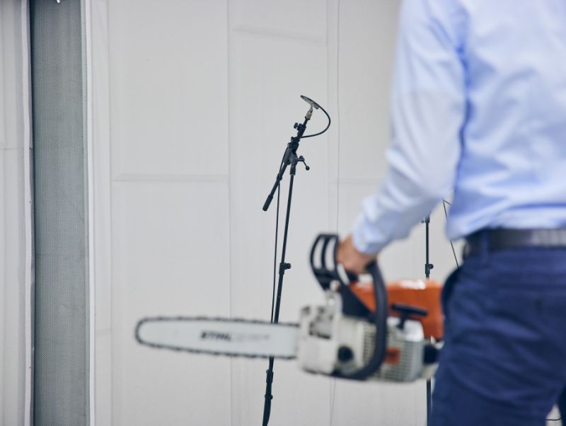 A chainsaw held by a partly shown figure identifiable as a man.
