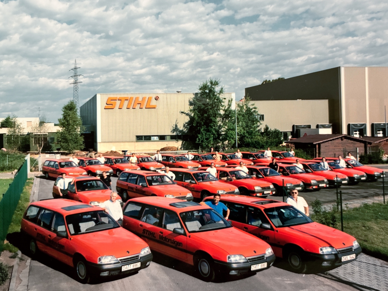 A fleet of red cars in front of a STIHL building.