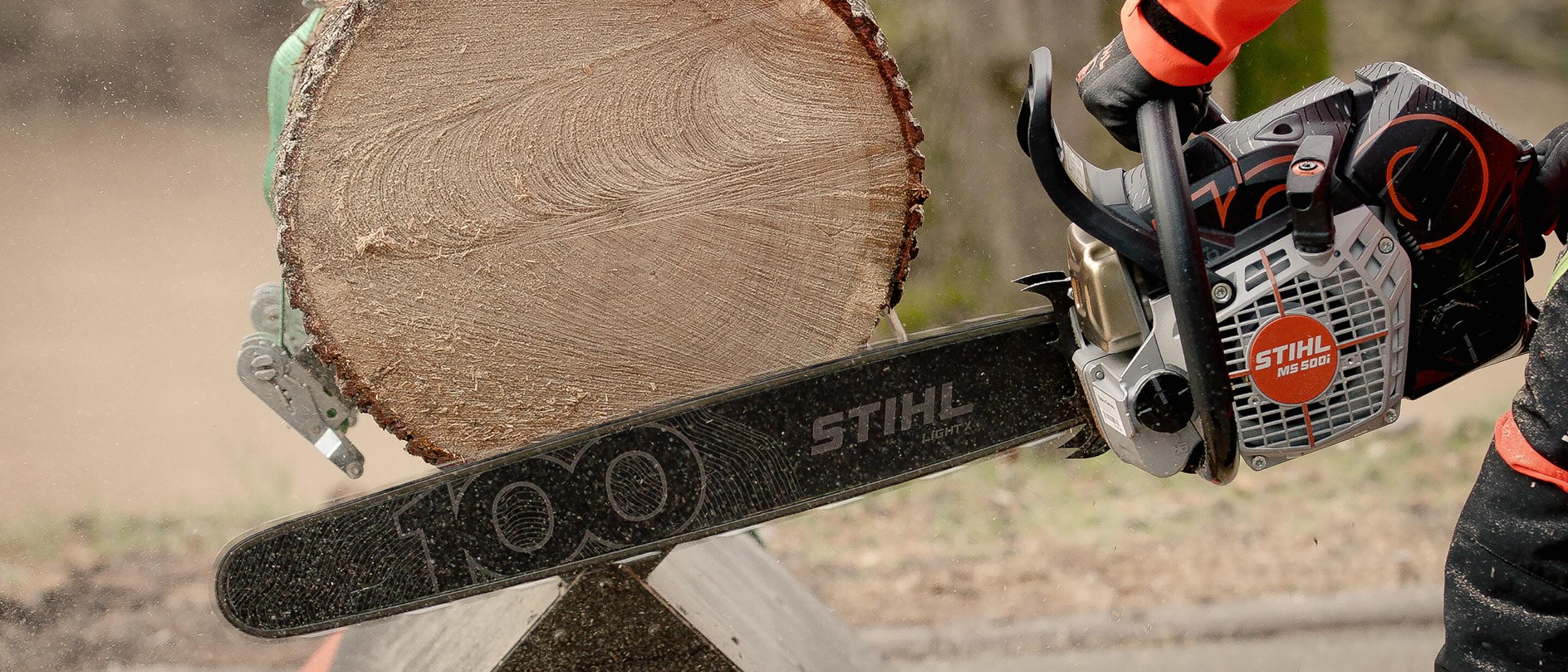 The STIHL anniversary chainsaw in action, cutting a tree trunk.
